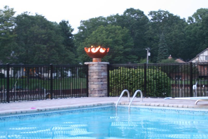 Waves Sculptural Fire Pit on stone pillar by pool