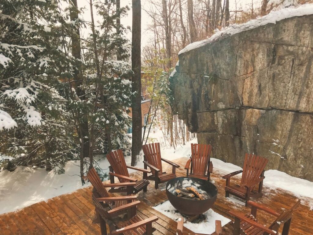 recycled steel Fire pit on wood deck with adirondack chairs and exposed rock